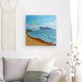 Carregar imagem no visualizador da Galeria, Coastal beach painting with waves, boats, mountains, and sun on white wall above gray couch