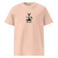 Cargar la imagen en la vista de la galería, Unisex organic cotton t-shirt in light peach with black cat fishing graphic and 'Fishy Business' text.