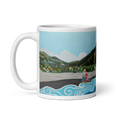 Cargar la imagen en la vista de la galería, White glossy 11 oz coffee mug with colorful beach scene painting of couple, ocean waves, mountains, and village