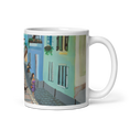 Load image into Gallery viewer, white ceramic mug with colorful street scene artwork featuring a woman in purple dress and buildings
