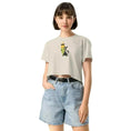 Carregar imagem no visualizador da Galeria, Woman wearing beige crop top with cartoon pencil and cat, paired with high-waisted denim shorts