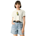 Carregar imagem no visualizador da Galeria, Woman wearing ecru crop top with cartoon surfboard and black cat graphic, denim shorts